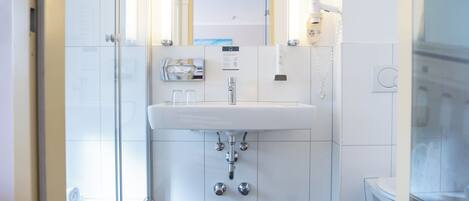 Un baño moderno con un lavabo blanco, un espejo y un inodoro.