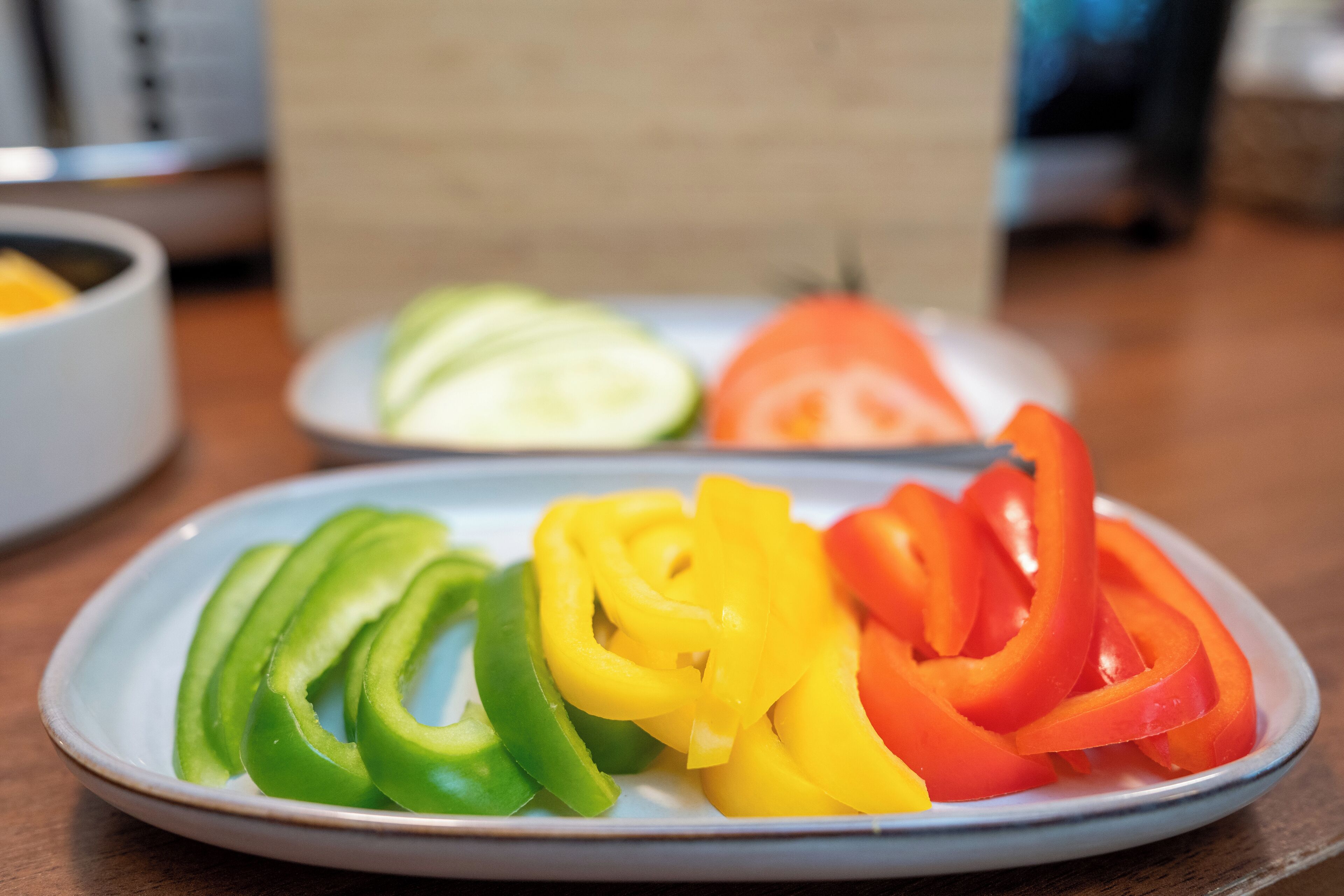 Un plato con pimientos en rodajas, verdes, amarillos y rojos.