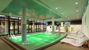 A spa area with a heated pool, lounge chairs, and a large window with a view of the outdoors. - Grand Hotel La Chiusa di Chietri (Alberobello)