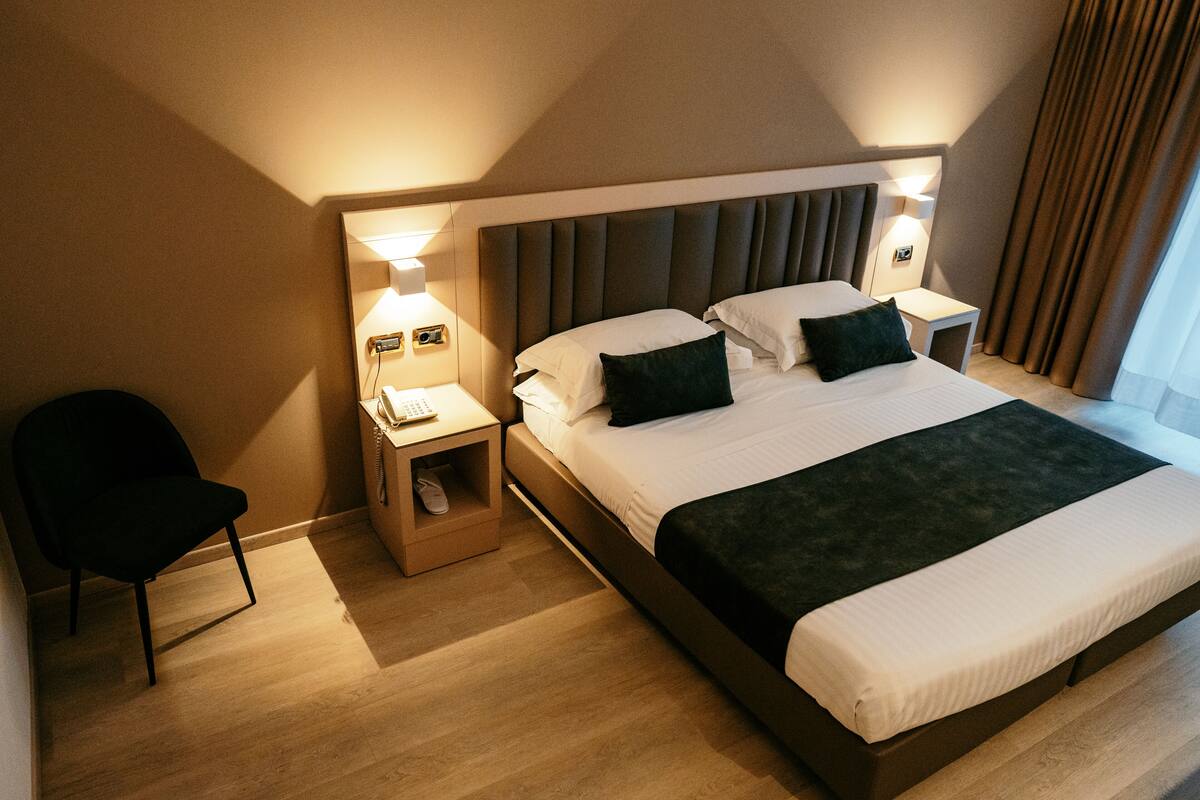 Une chambre d’hôtel avec un grand lit, des tables de chevet, une chaise et une petite table de nuit avec une lampe.