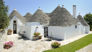 A traditional stone-roofed building with a patio area, outdoor seating, and potted plants. - Grand Hotel La Chiusa di Chietri (Alberobello)