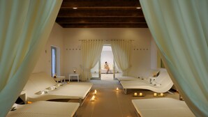 A spa room with two reclining beds, a small table, and candles. - Grand Hotel La Chiusa di Chietri (Alberobello)