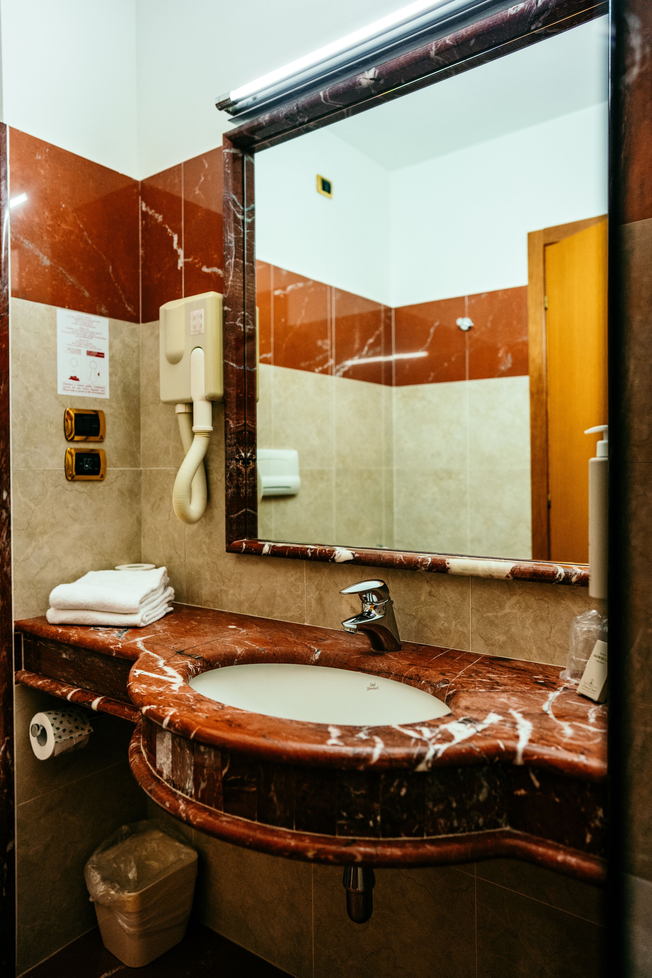 Ein Badezimmer mit Marmorwaschbecken, einem Spiegel, einem Telefon und einem Mülleimer.