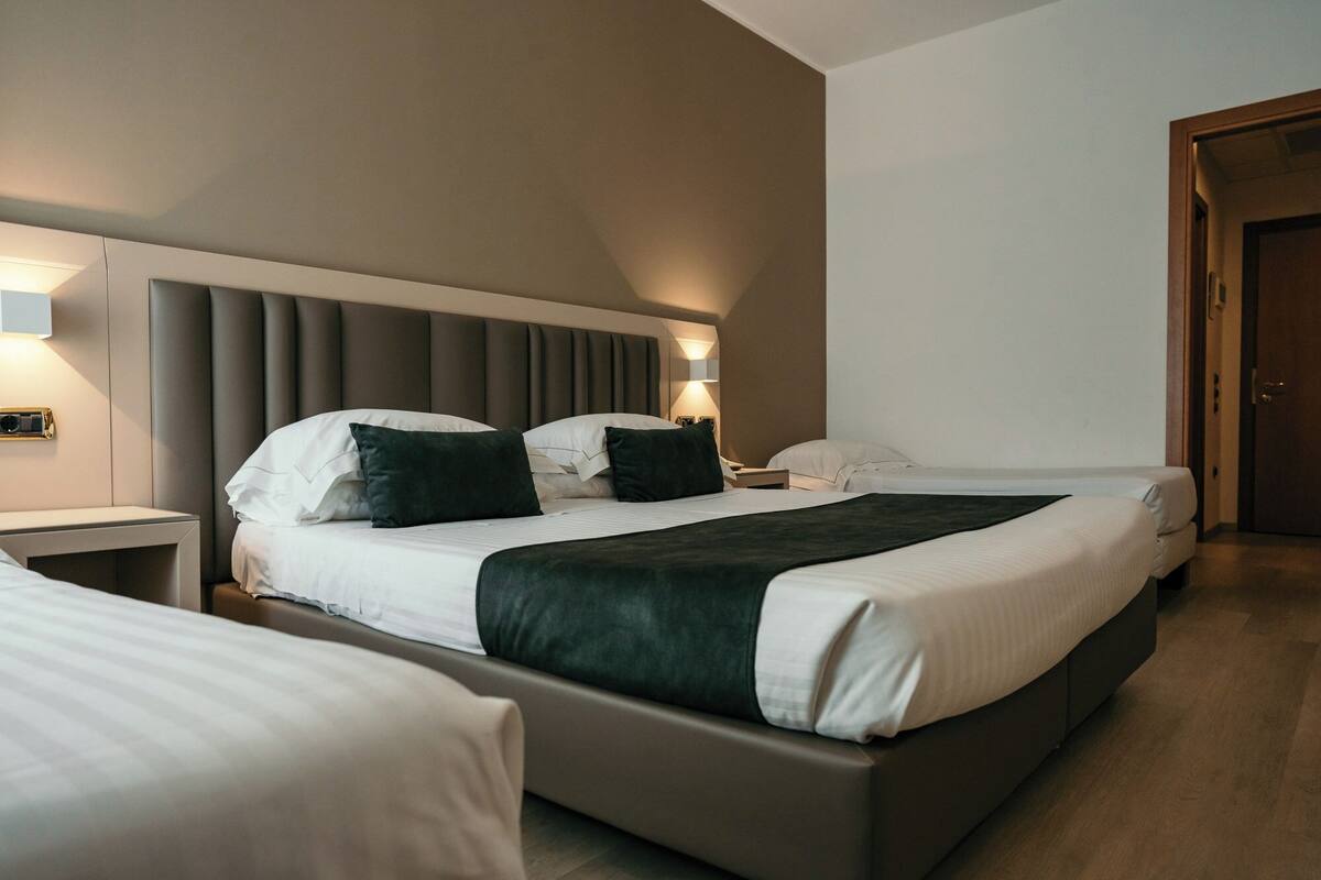 A modern hotel room with a large bed, bedside tables, and a nightstand.