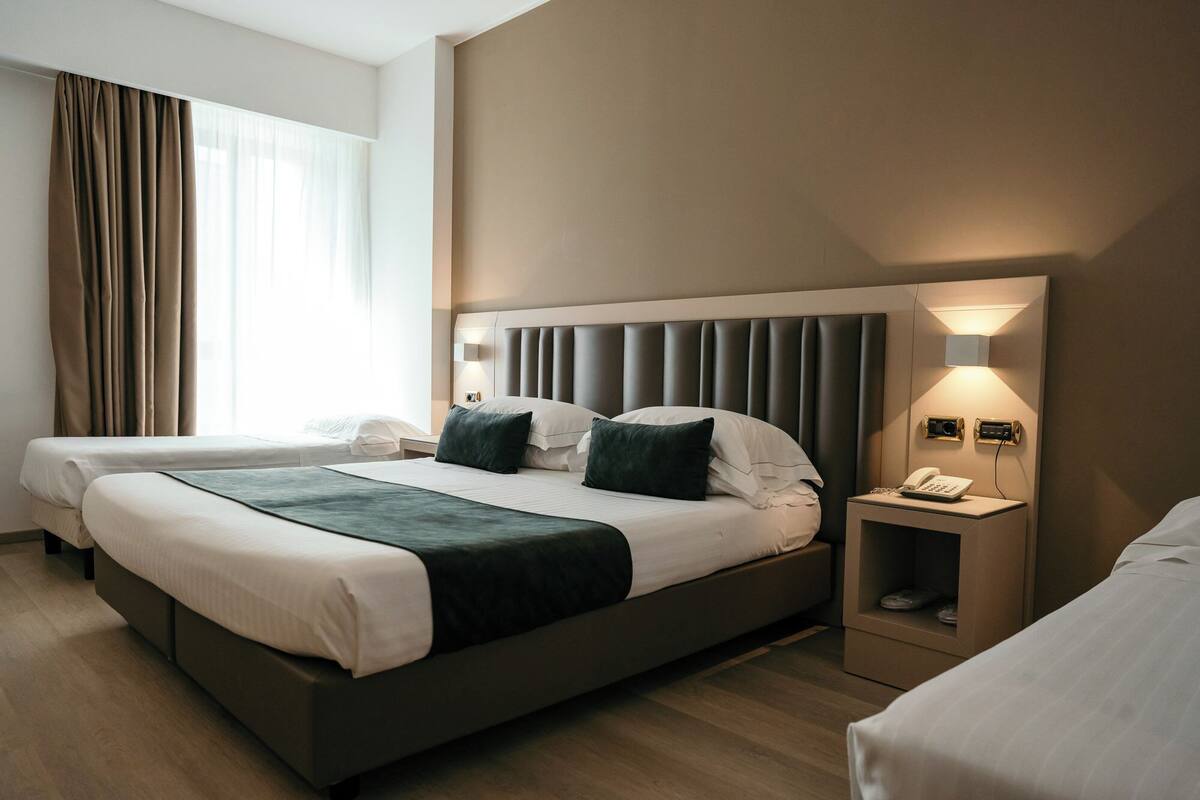 A hotel room with a large bed, two bedside tables, a phone, and a lamp.