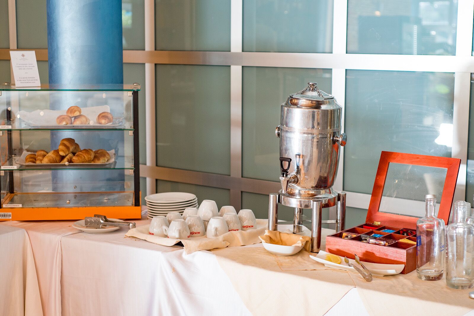 A buffet setup with croissants, coffee pots, and a variety of dishes.