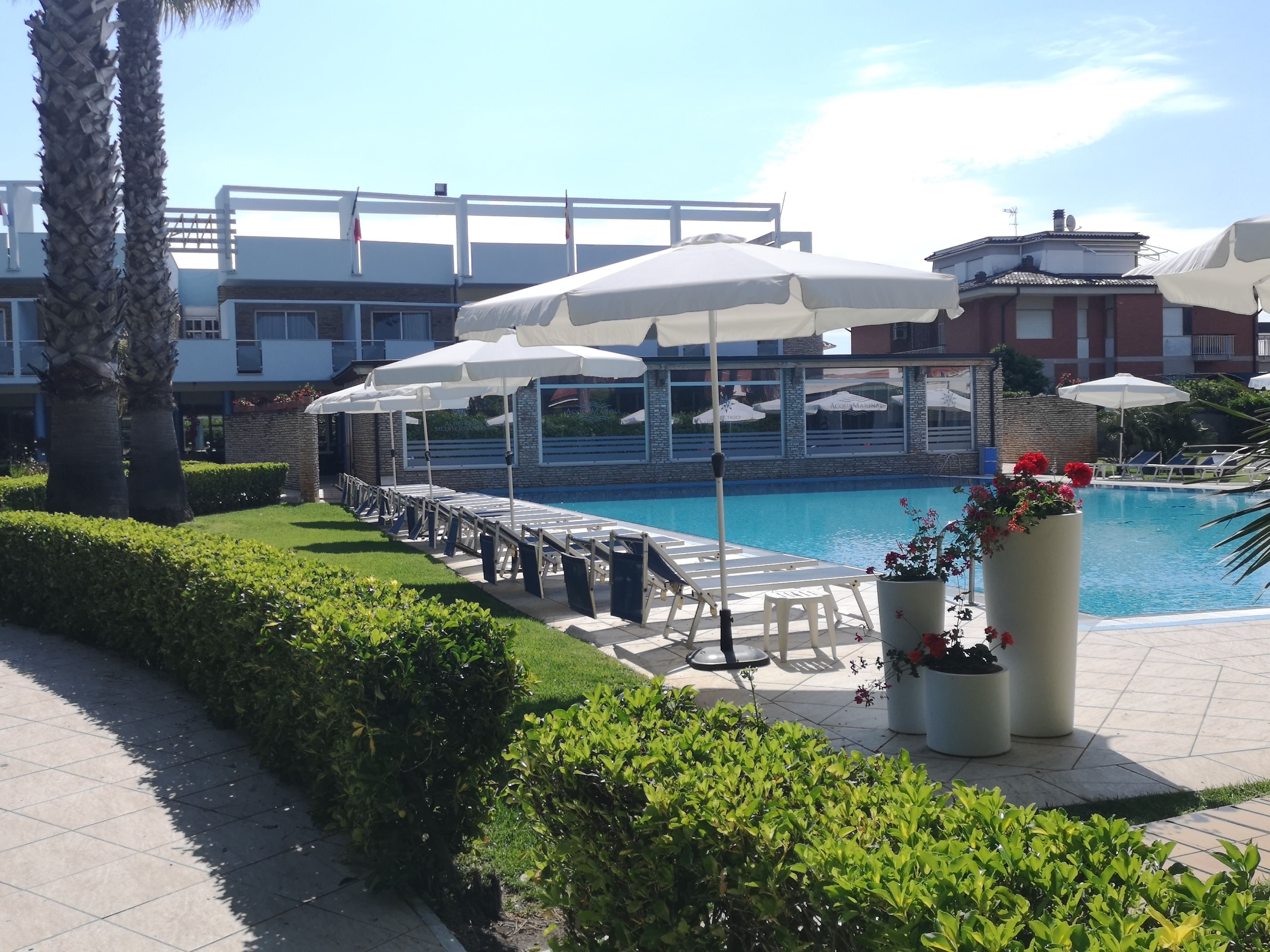 Un espace aménagé au bord de la piscine, avec des parasols, des chaises longues et une piscine.