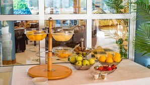 A buffet setup with various fruits and a fruit bowl on a table.