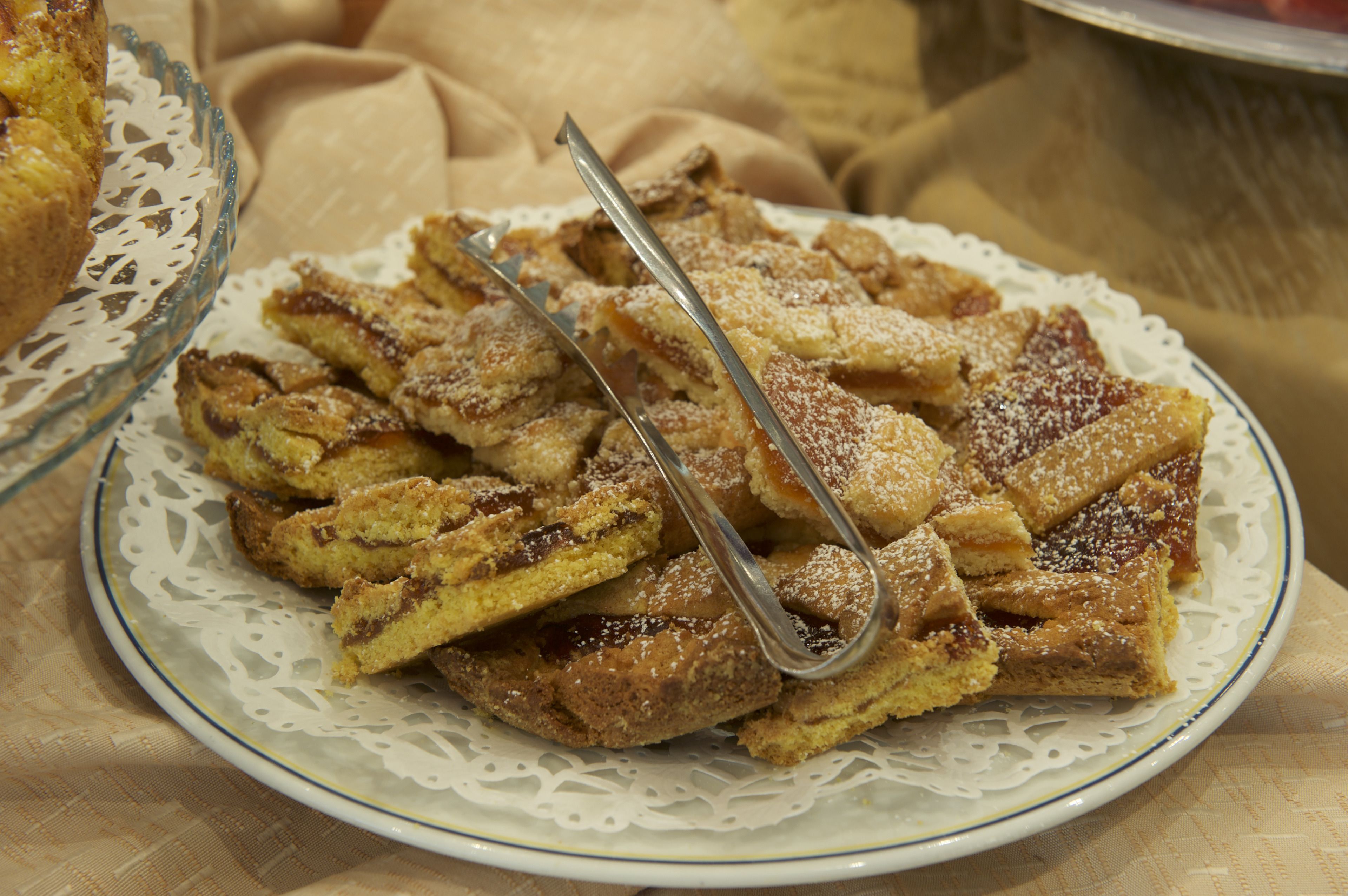 A plate of bread with a knife and tongs, placed on a lace doily.