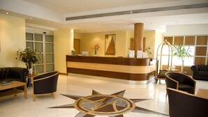A hotel lobby with a reception desk, seating area, and a large decorative floor design.