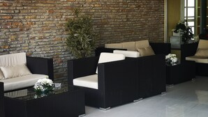 A modern lounge area with wicker furniture, a stone wall, and a potted plant.