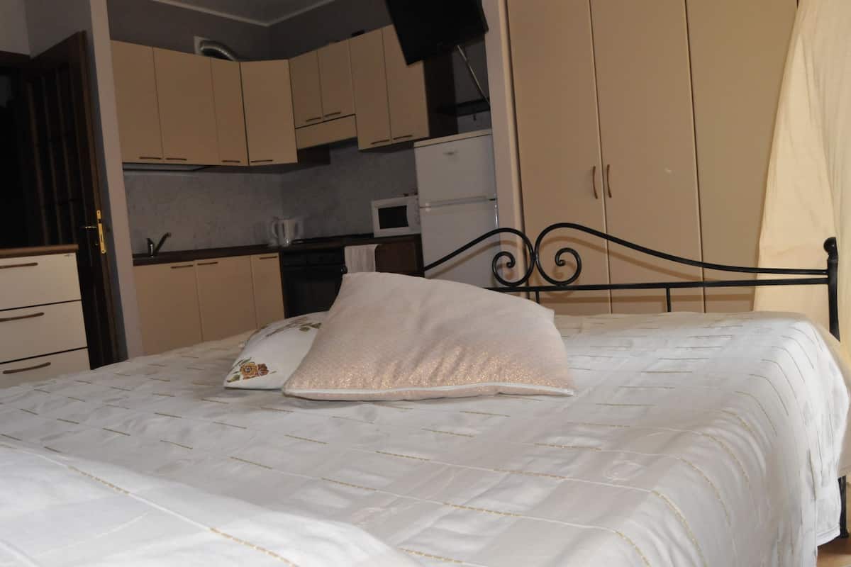 Ein Schlafzimmer mit Bett, Kissen, Kleiderschrank und einer Küchenzeile.
