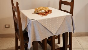 Uma mesa de jantar com toalha de bolinhas, duas cadeiras de madeira e um quadro na parede acima.
