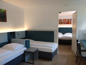 Une chambre d’hôtel avec deux lits simples, une petite table, un bureau et une chaise.