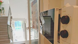 Una escalera conduce a un área exterior, una puerta de cristal y un termostato en la pared.