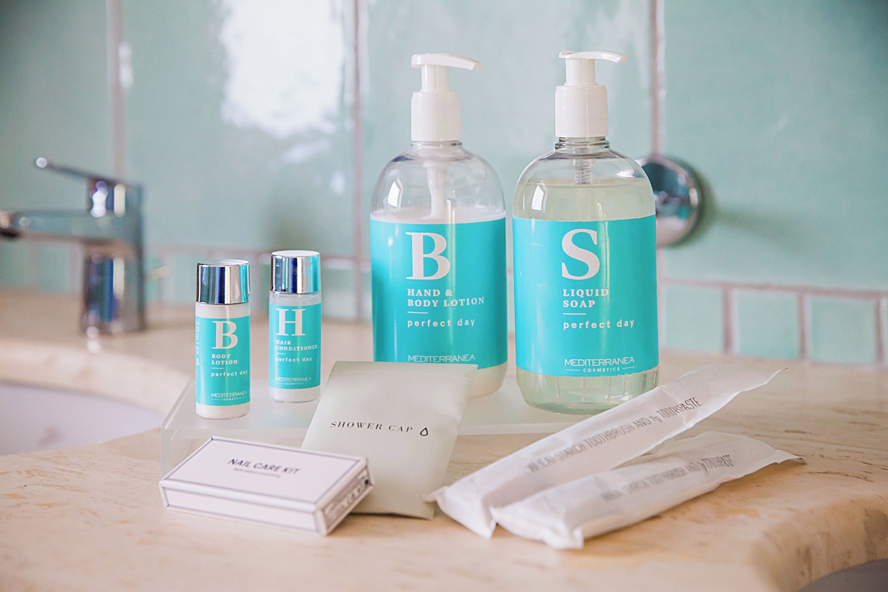 A bathroom vanity with toiletries including body lotion, hand soap, and a shower cap.