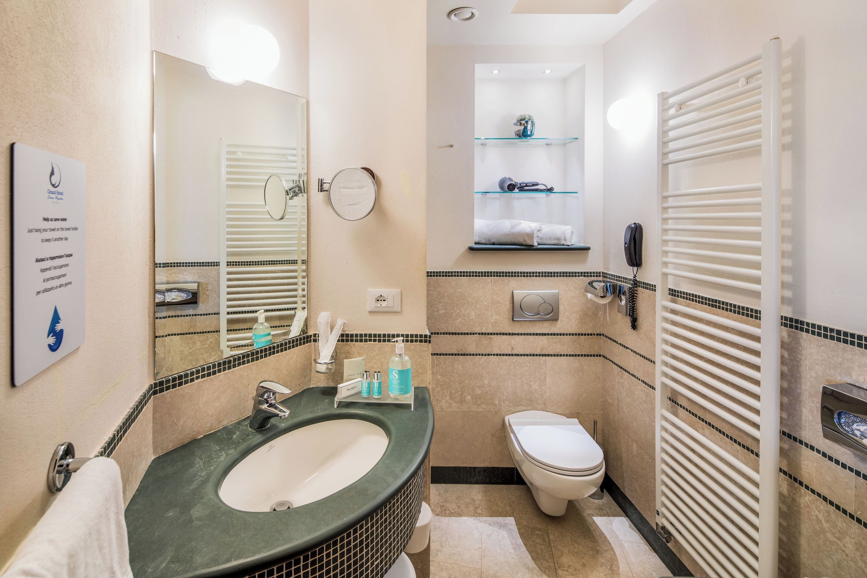 Un bagno con lavandino, specchio, water e portasciugamani.
