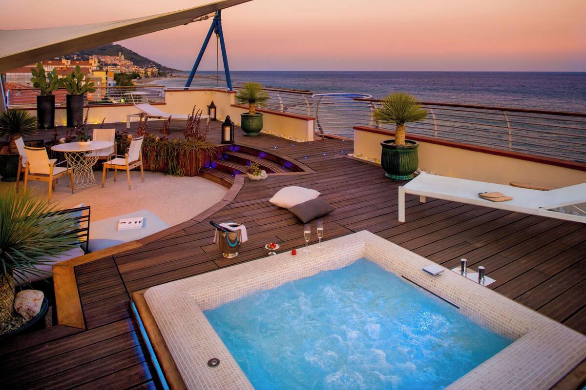 A rooftop terrace with a hot tub, seating area, and potted plants.