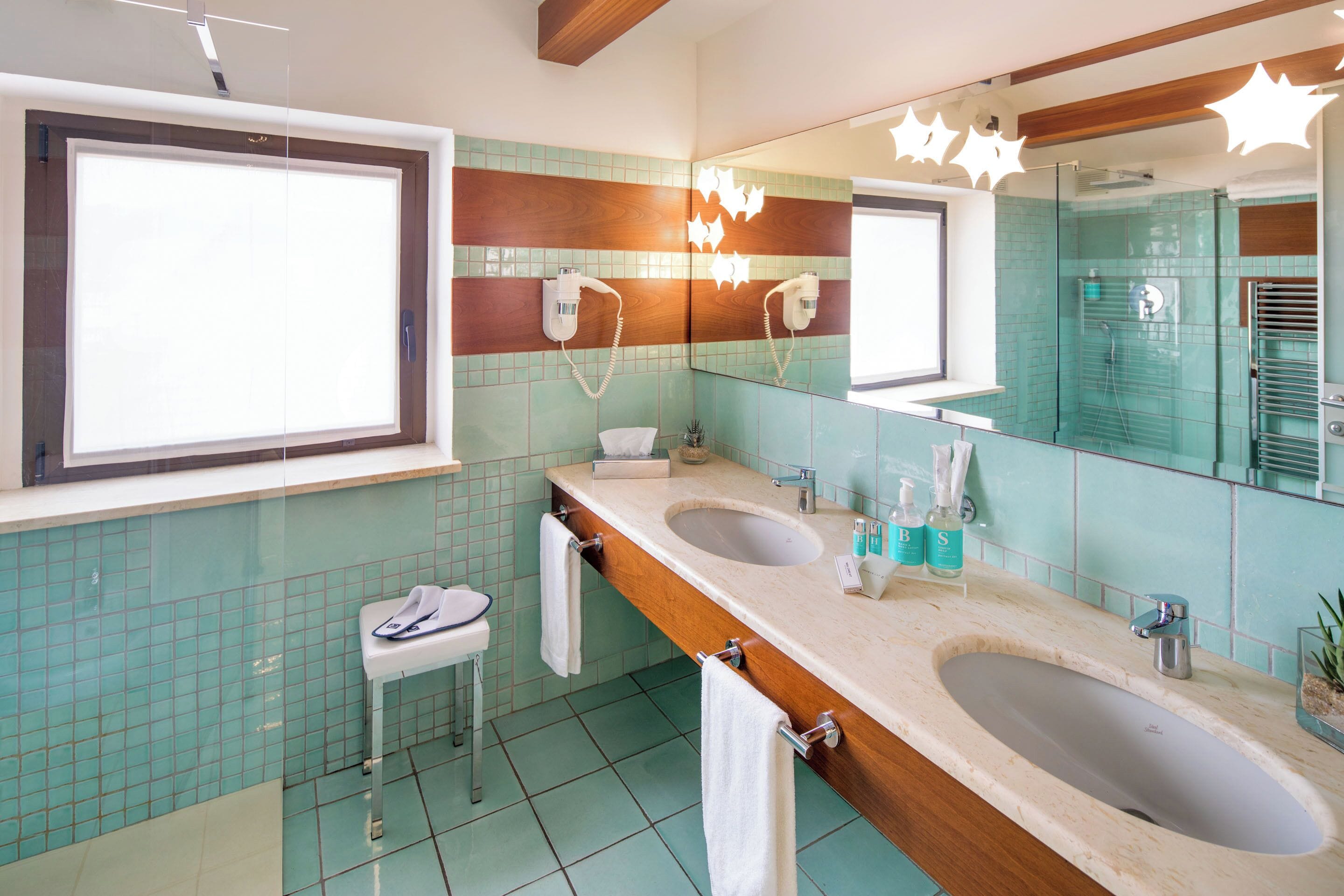 Un bagno con due lavabi, uno specchio e un asciugacapelli montato a parete.