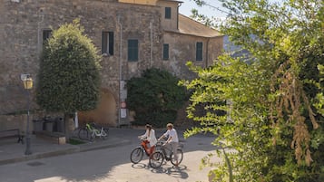 A street scene with two cyclists, a stone building, and a bench.