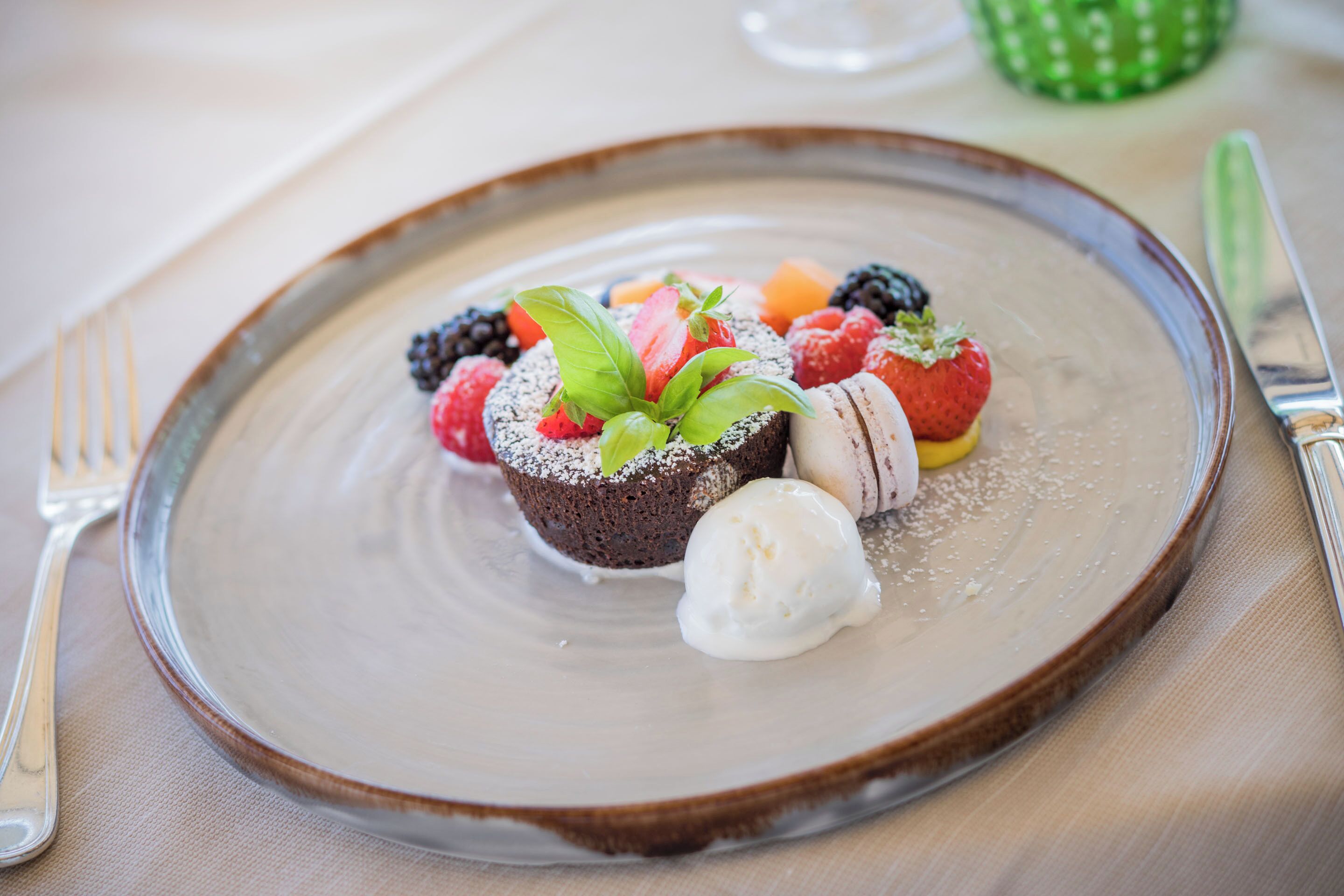 Un plato de postre con diversas frutas y una bola de helado.