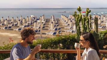 Two people seated at a round table with a view of the beach and cacti in the background.