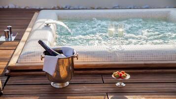 Ein Whirlpool mit Champagner und Erdbeeren auf einer Holzterrasse.