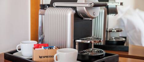 A Nespresso coffee machine on a tray with two white cups and a Nespresso capsule box.