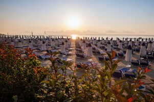Playa privada, arena negra, sillas reclinables de playa, sombrillas