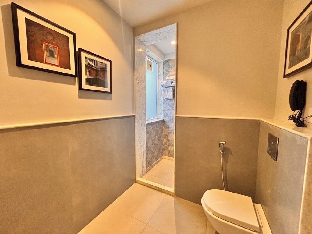 A bathroom with a toilet, shower, and framed pictures on the wall.