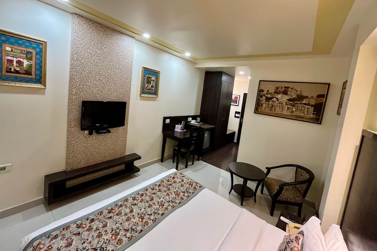 A hotel room with a bed, a TV, a desk, and a chair.