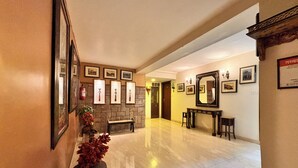A spacious lobby with a marble floor, a fireplace, framed pictures on the walls, and a large mirror. - Hotel Ratnawali (Jaipur)