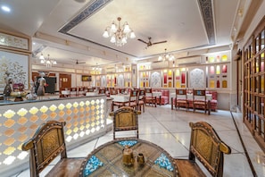 Un restaurante con una decoración interior tradicional, que presenta adornos ornamentales en las paredes, candelabros y diversas opciones de asientos.