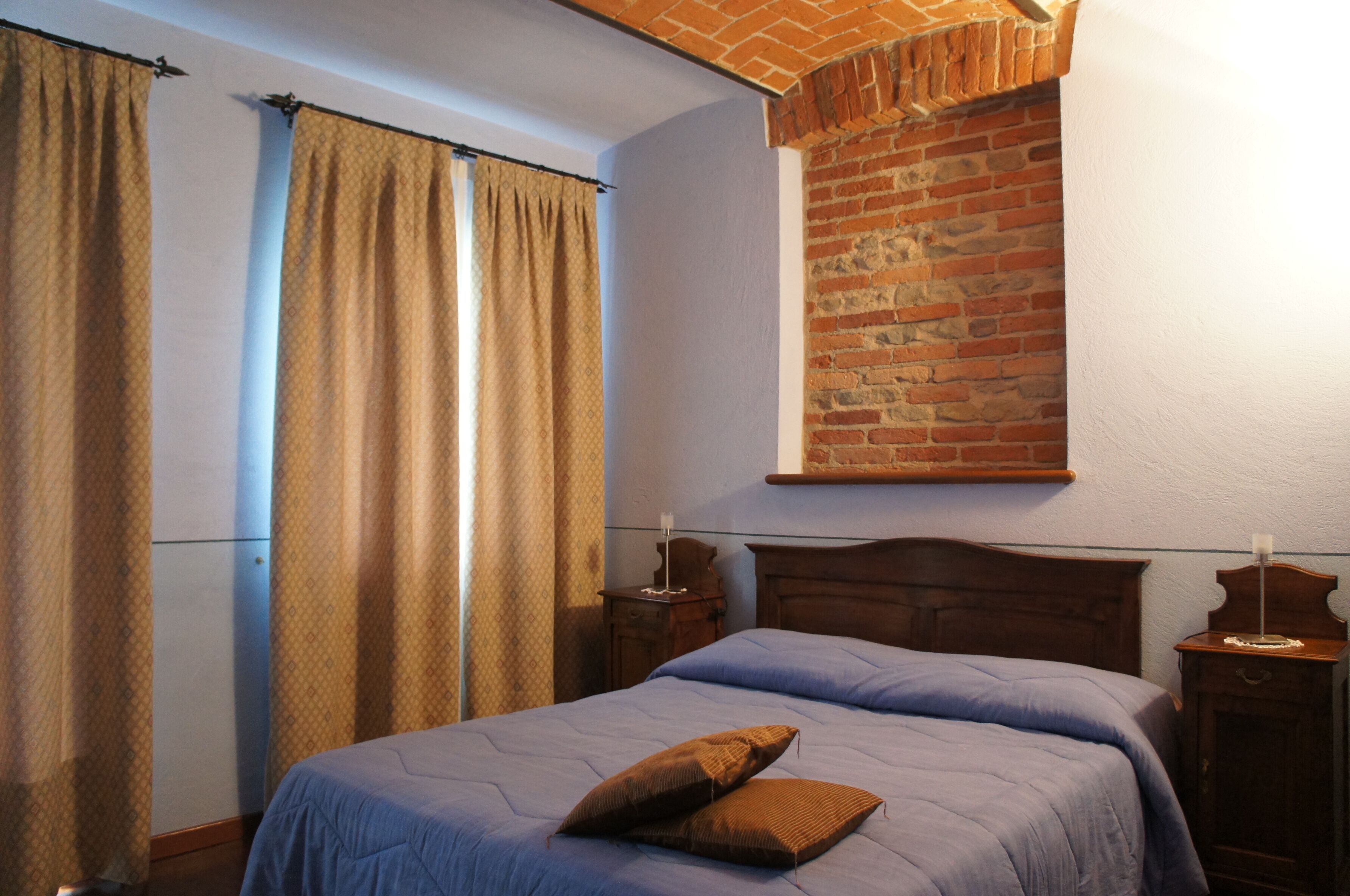 Un dormitorio con pared de ladrillo, estructura de cama de madera y mesita de noche.