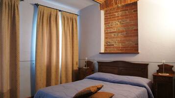 Un dormitorio con pared de ladrillo, estructura de cama de madera y mesita de noche.
