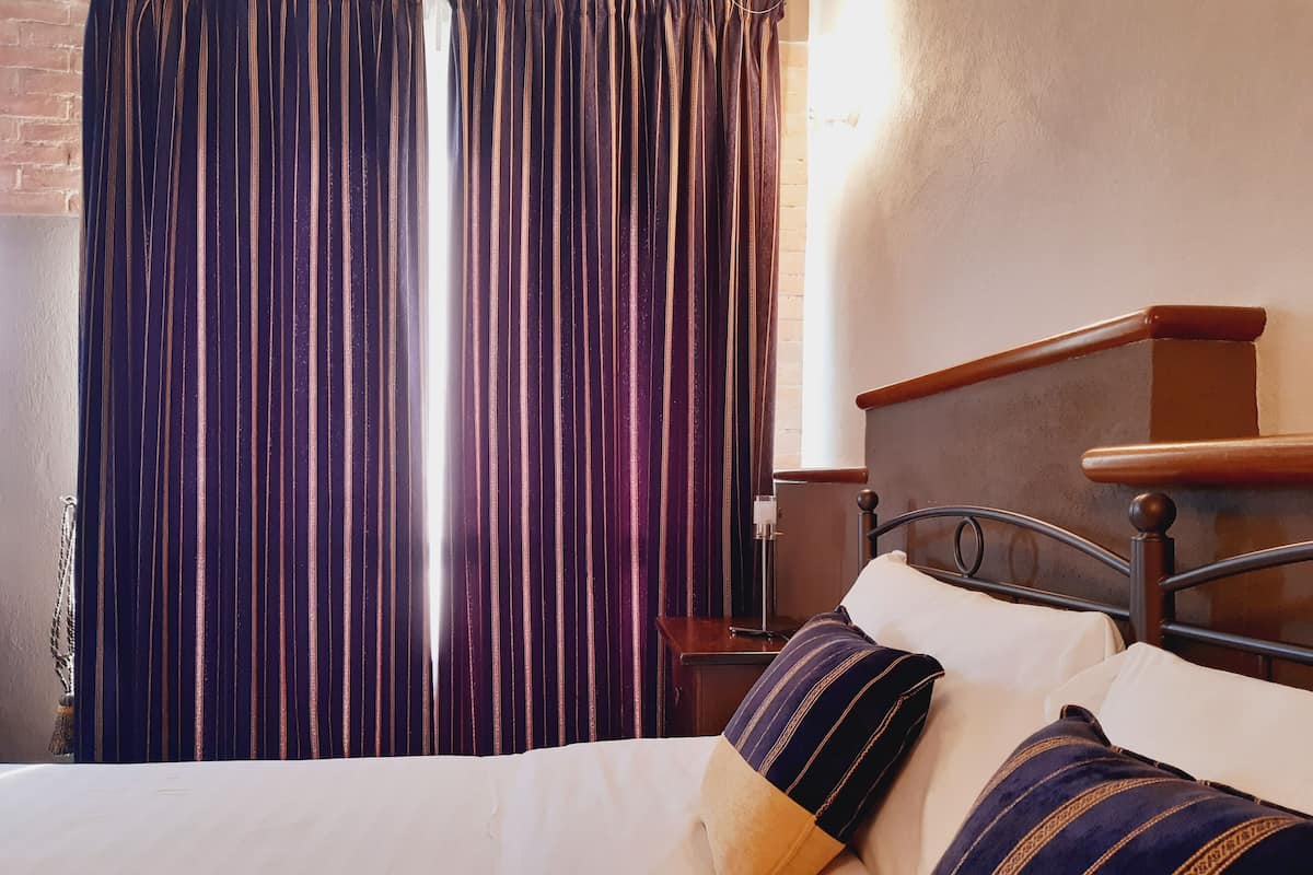 A bed with striped pillows, a wooden headboard, and a brick wall.