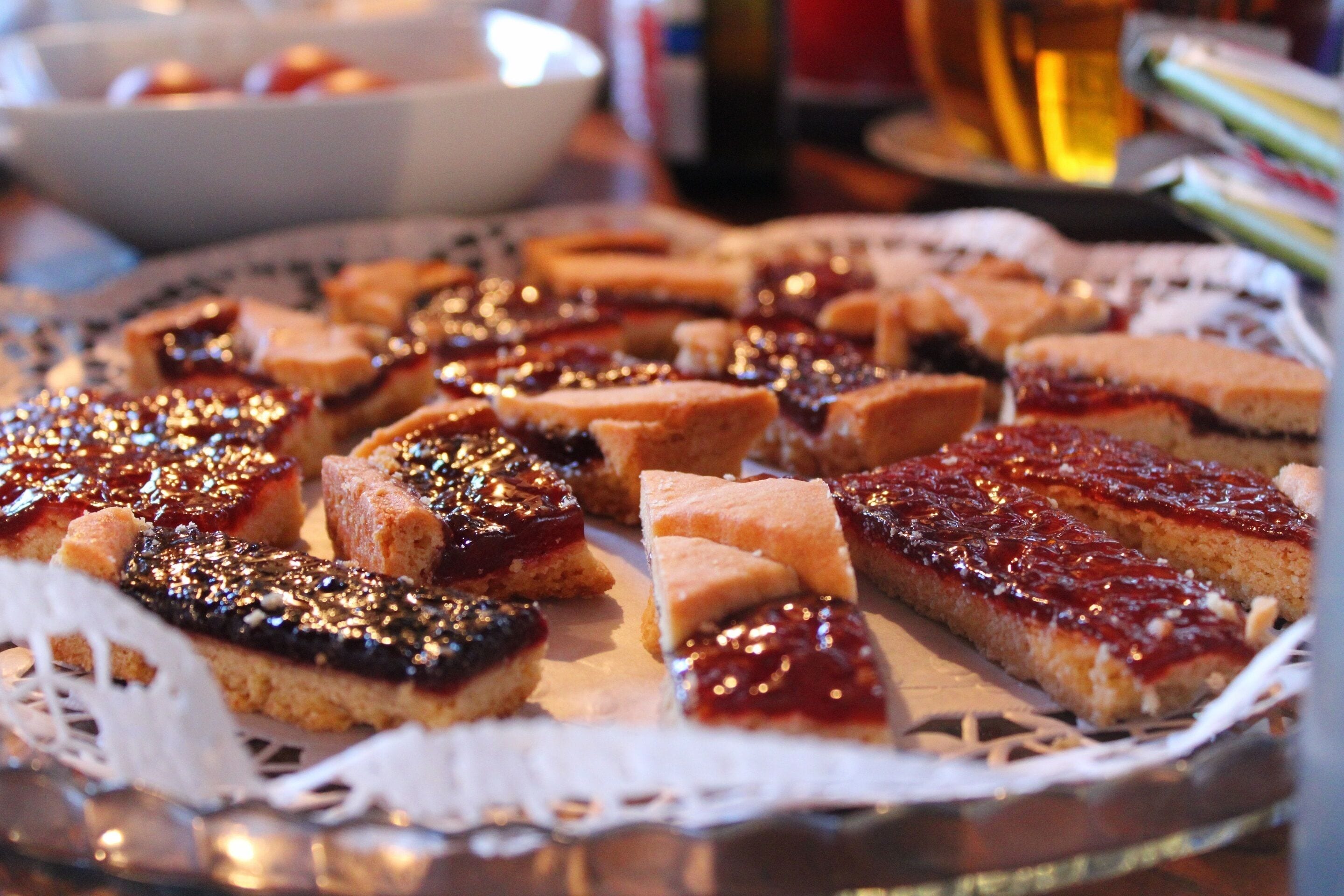 Variedad de postres en una bandeja, entre ellos pasteles y hojaldres con mermelada y nueces.