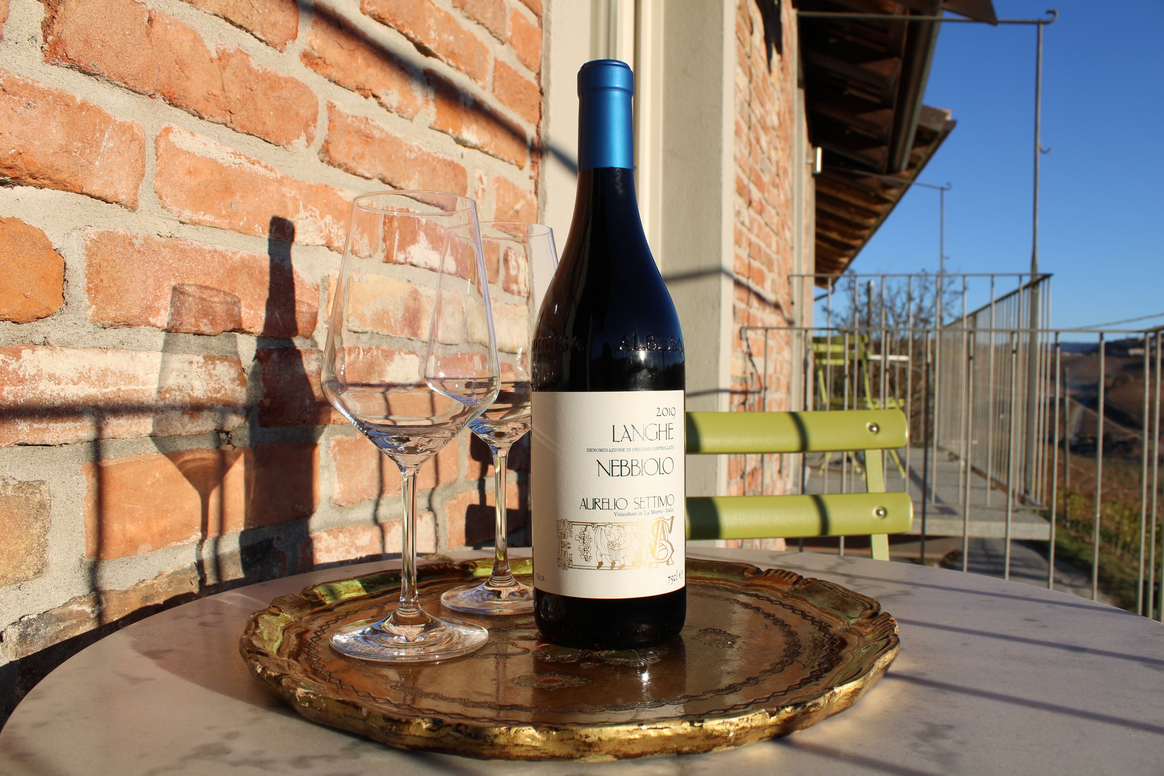 A bottle of wine and two glasses on a table with a brick wall background.