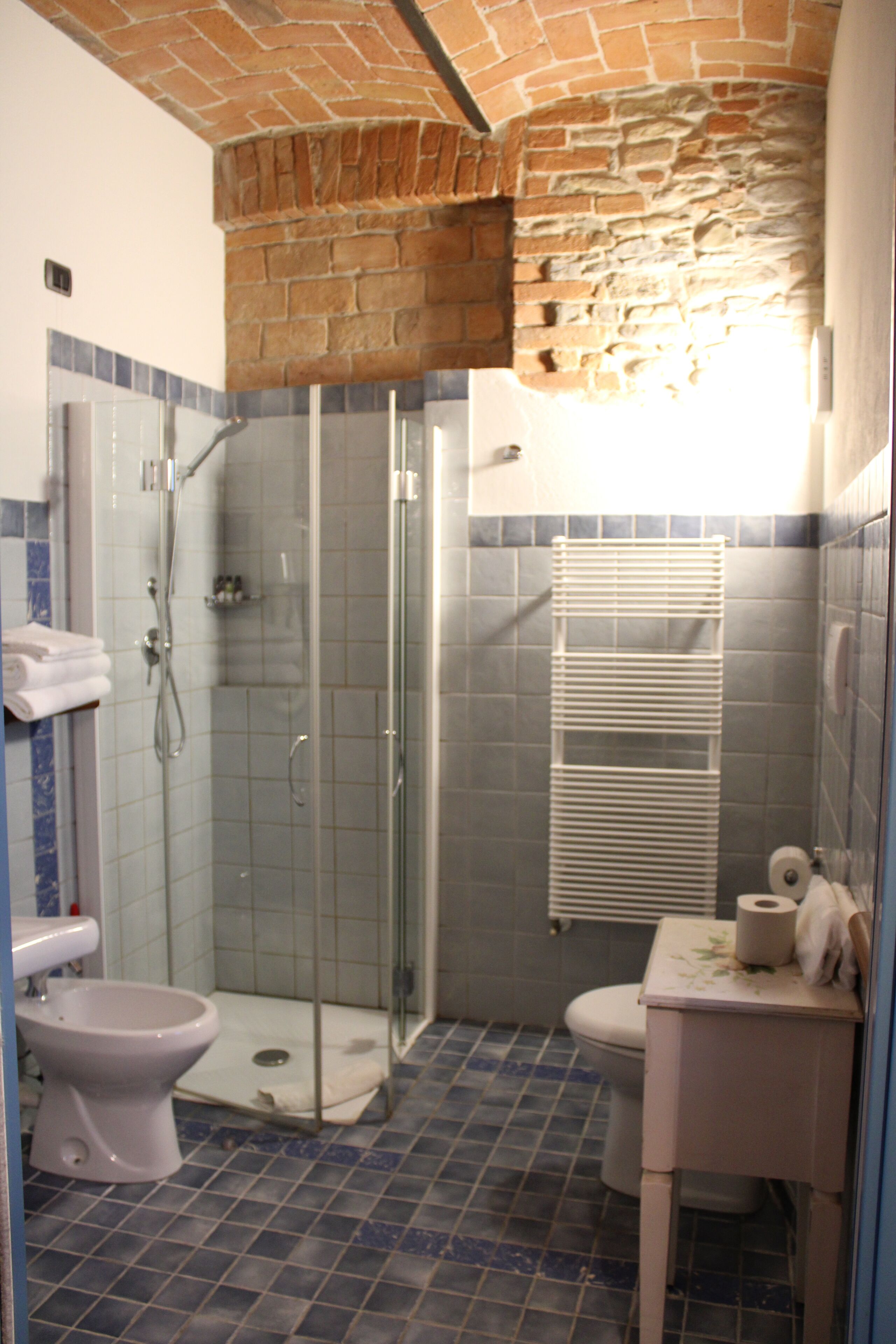A bathroom with a glass-enclosed shower, a toilet, and a sink.