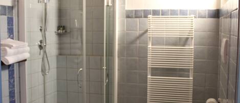 A bathroom with a glass-enclosed shower, a toilet, and a sink.