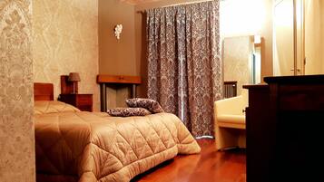 Une chambre à coucher avec un lit en bois, une table de chevet avec une lampe, un miroir et une fenêtre avec des rideaux.