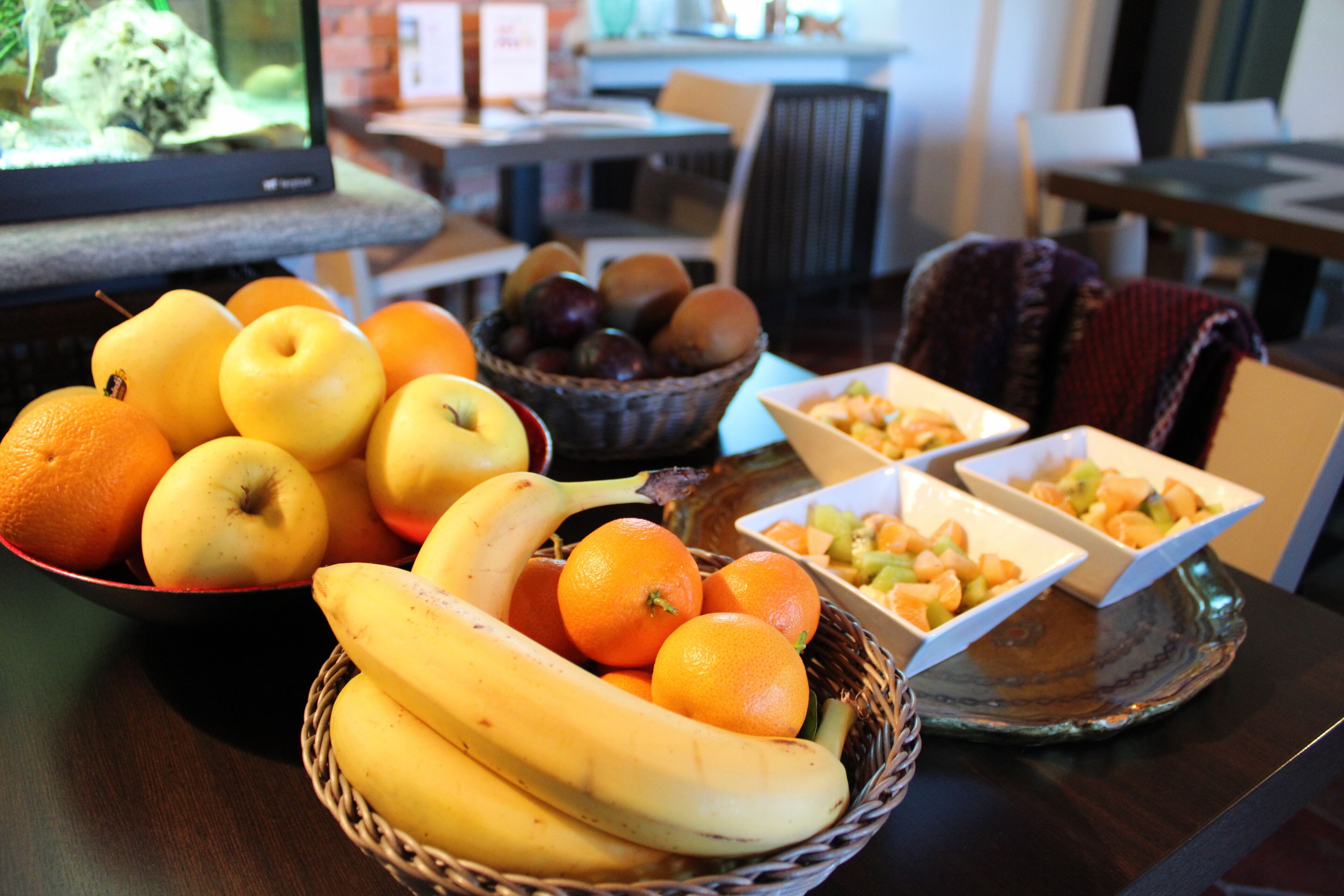 Una mesa de comedor con un frutero que contiene manzanas, naranjas y plátanos.
