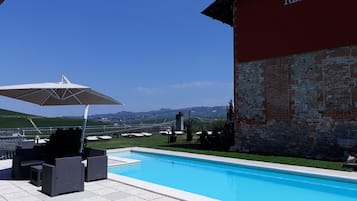 Una piscina al aire libre, sombrillas, sillones reclinables de piscina