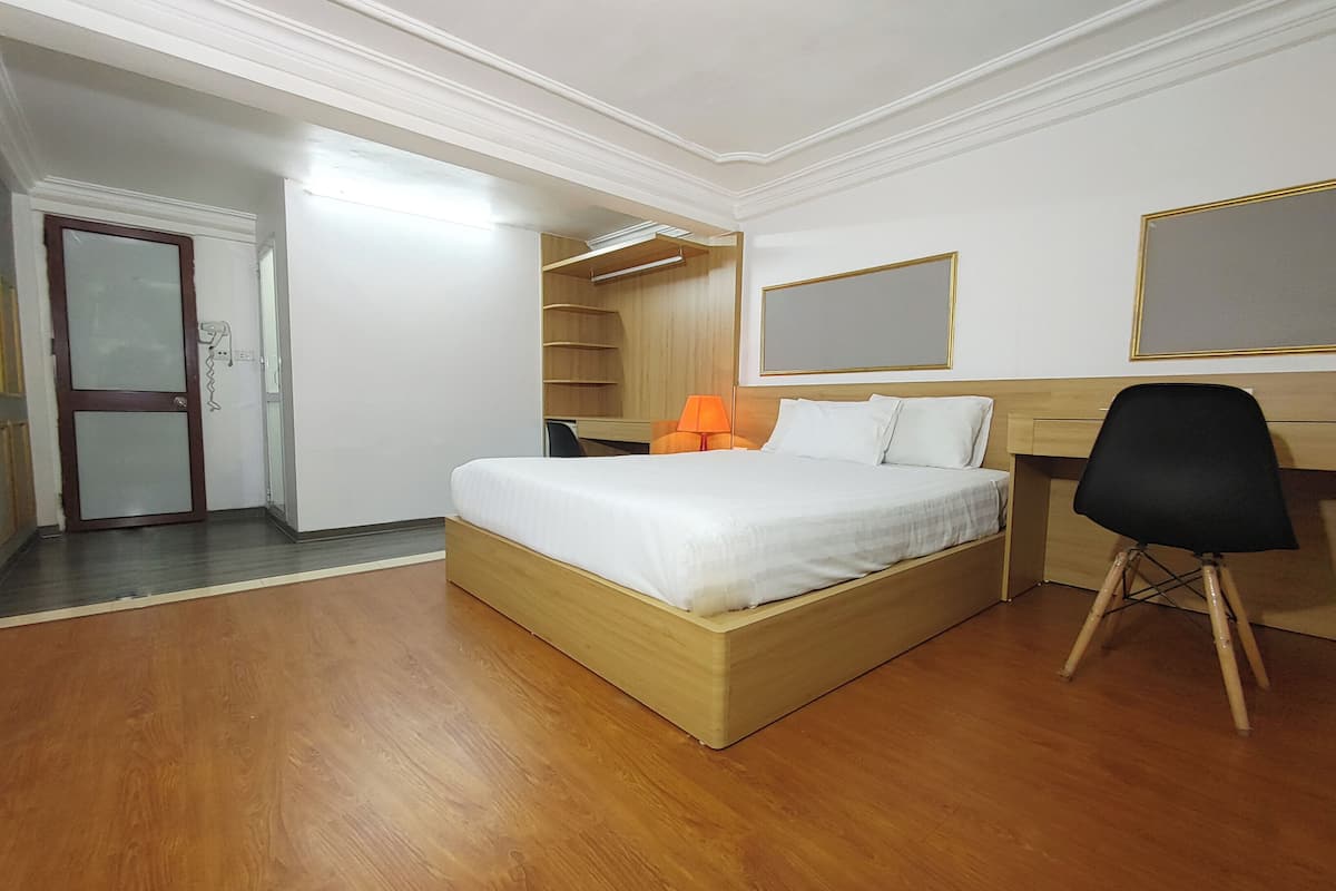 A modern hotel room with a wooden bed, a desk, and a chair.