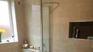 A bathroom with a glass-enclosed shower, a toilet, and a shelf with toiletries. - Hanoi Discovery Hotel (Hanoi)