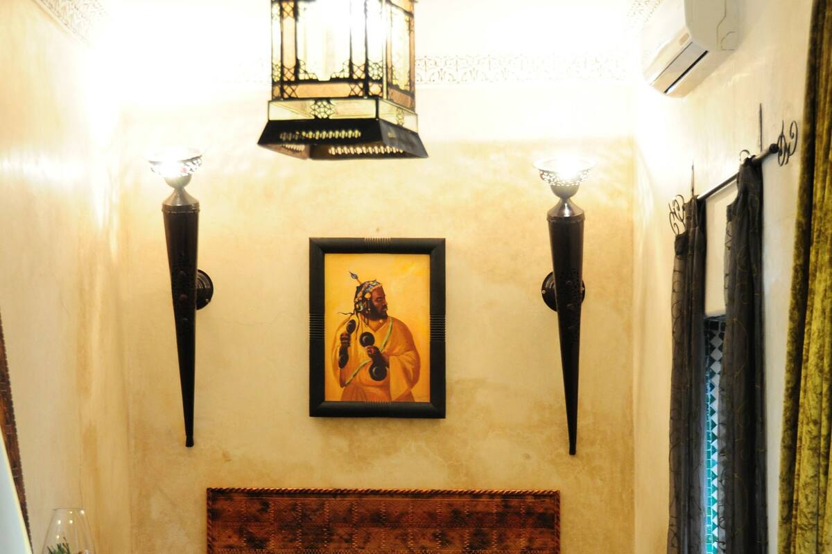 A bedroom with a large bed, a decorative lantern, a framed picture on the wall, and a patterned rug.