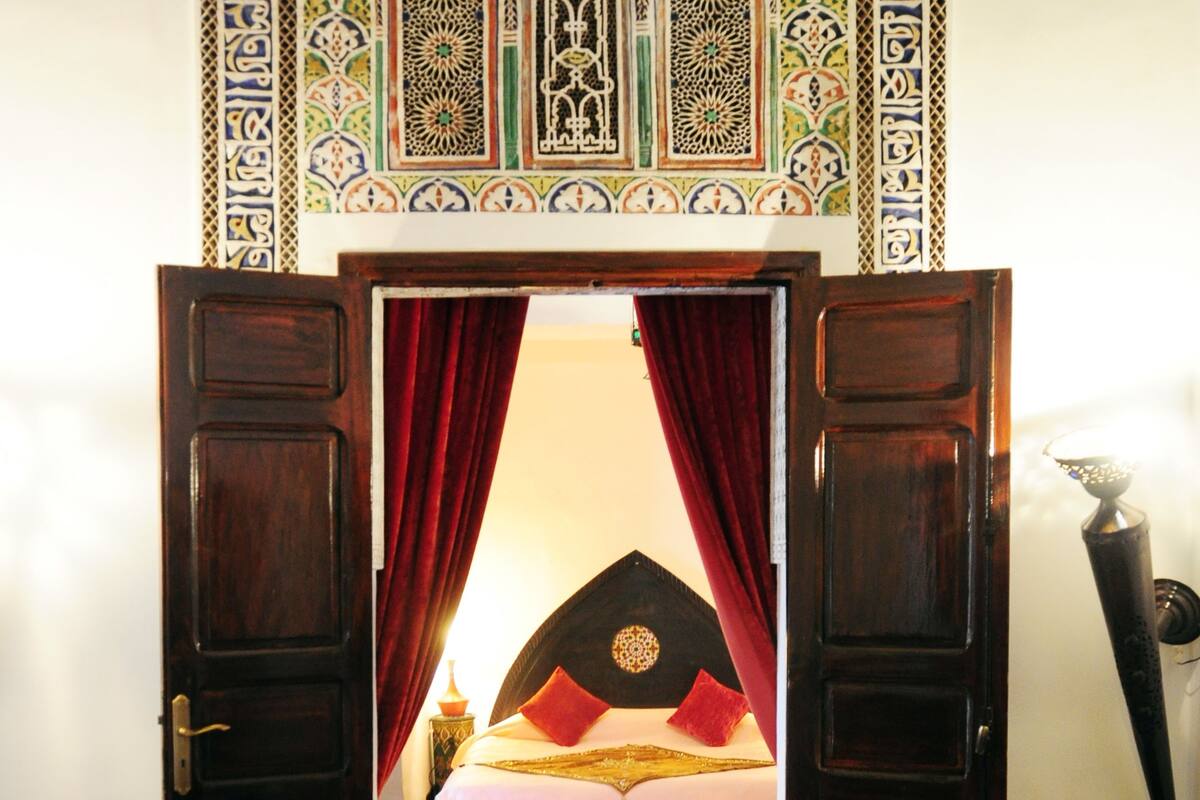 A room with a bed, a red carpet, a glass table, and a decorative wall.