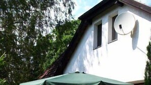 Een huis met een schotelantenne, buiten zitplaatsen en potplanten.