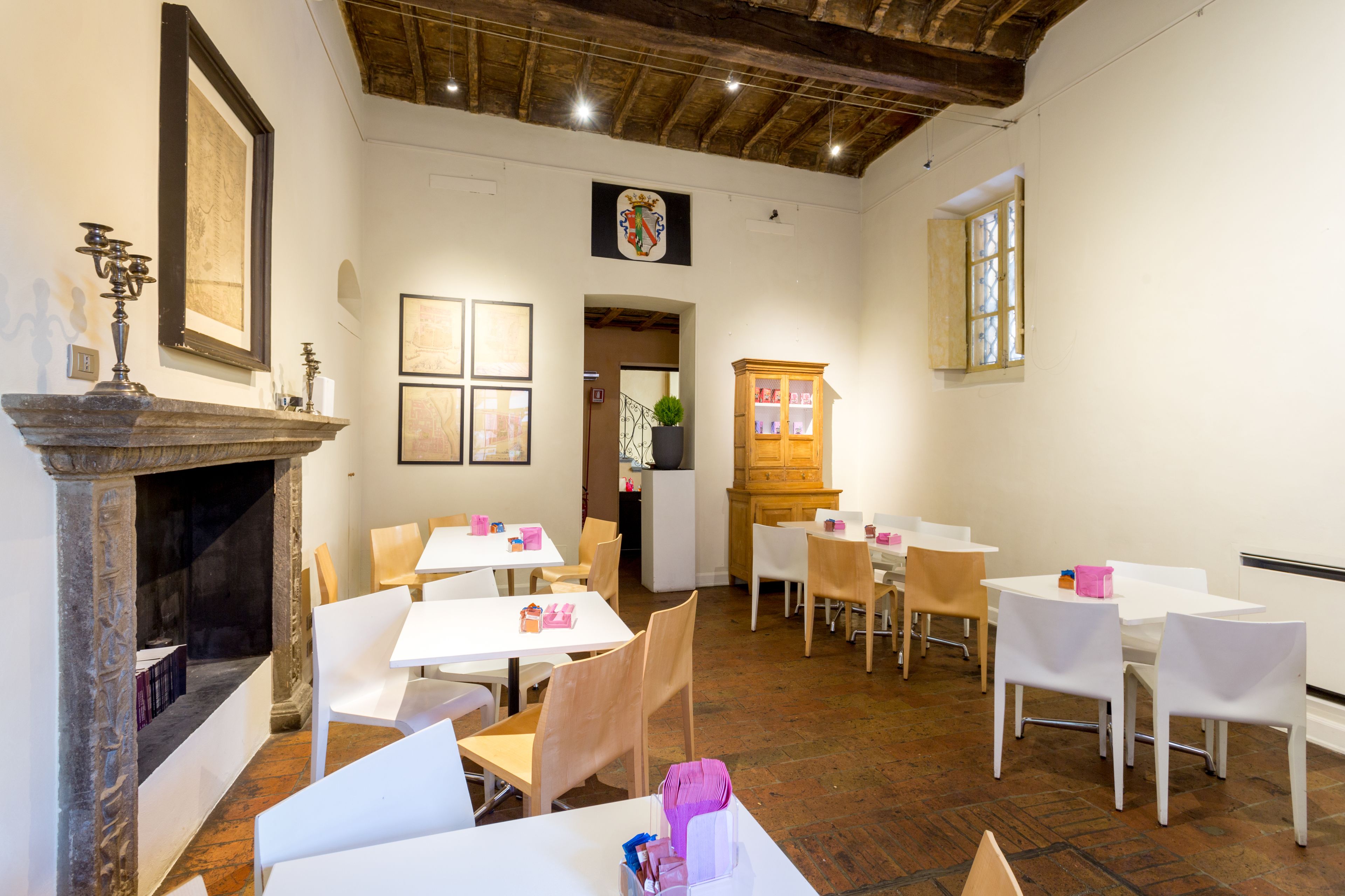 Un espace repas avec des tables et des chaises blanches, une cheminée et un buffet en bois.