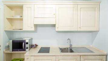 A compact kitchen with a microwave, a sink, and wooden cabinets.